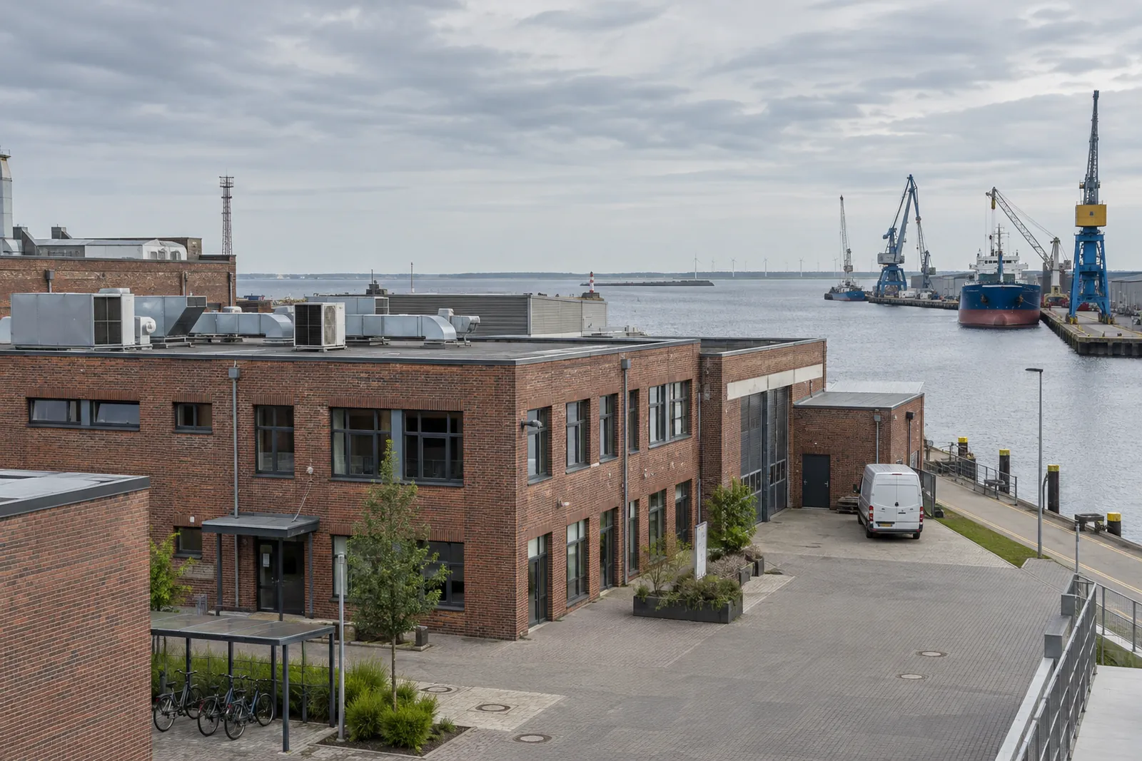 Backsteingebäude mit Lüftungsanlagen auf dem Flachdach vor dem Hafen von Emden