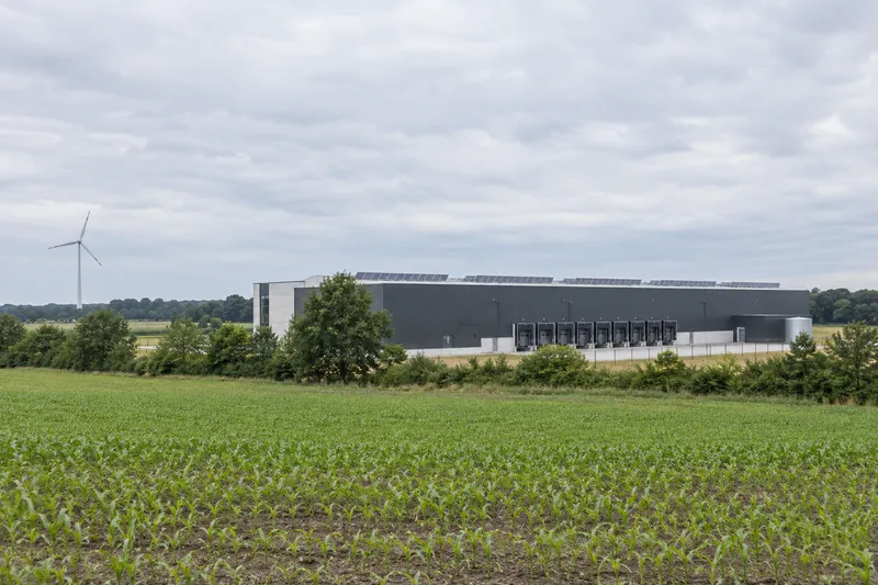Gewerbehalle mit Solaranlage am Dachrand vor einem flachen Feld im Oldenburger Münsterland