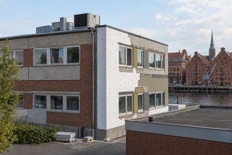 Gewerbebau aus den 1970er Jahren mit teilgedämmter Fassade und neuer Wärmepumpe auf dem Dach in einer niedersächsischen Stadt
