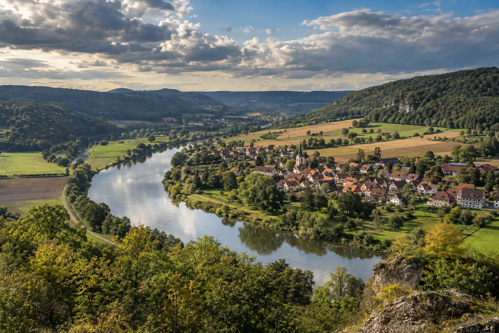 Weserbergland mit Fluss, Fachwerkdorf und bewaldeten Hügeln