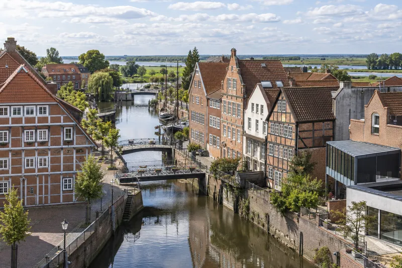 Backstein- und Fachwerkhäuser am Fleth in der Altstadt von Buxtehude mit moderner Gewerbebauten am Bildrand