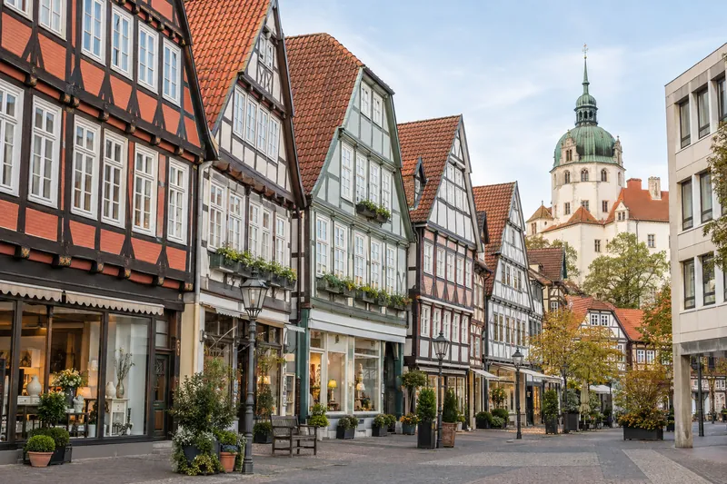 Fachwerkhäuser mit Ladengeschäften in der Celler Altstadt, im Hintergrund der Schlossturm und ein moderner Bürobau