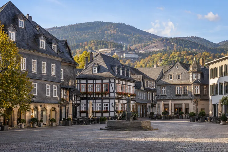 Fachwerkhäuser mit Schieferfassaden am Marktplatz von Goslar, im Hintergrund der bewaldete Rammelsberg