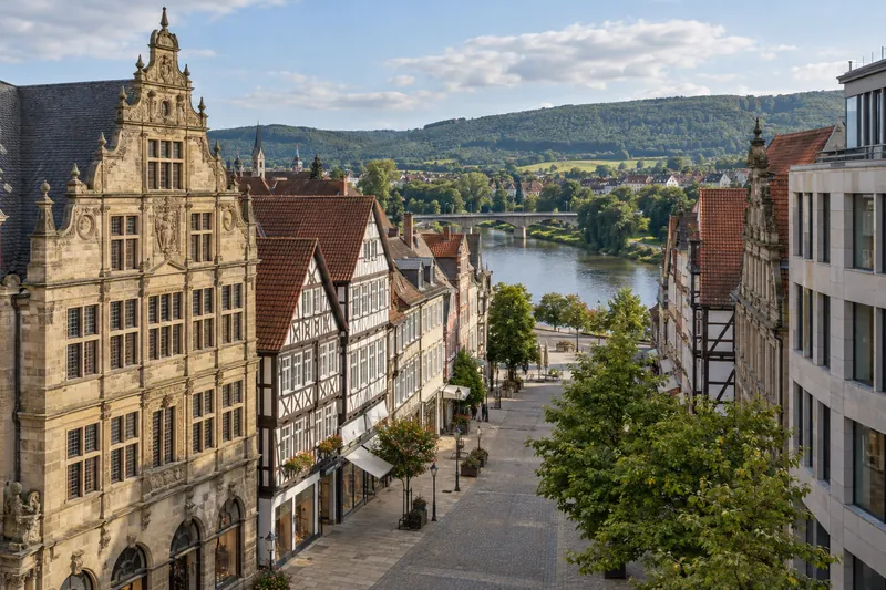 Renaissance- und Fachwerkhäuser in der Hamelner Altstadt mit Geschäftsgebäuden und dem Weserbergland im Hintergrund