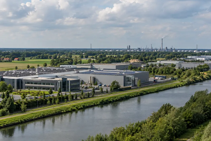 Moderne Gewerbehallen mit Solardächern und Bürotrakt am Dortmund-Ems-Kanal bei Lingen, im Hintergrund Industrieanlagen