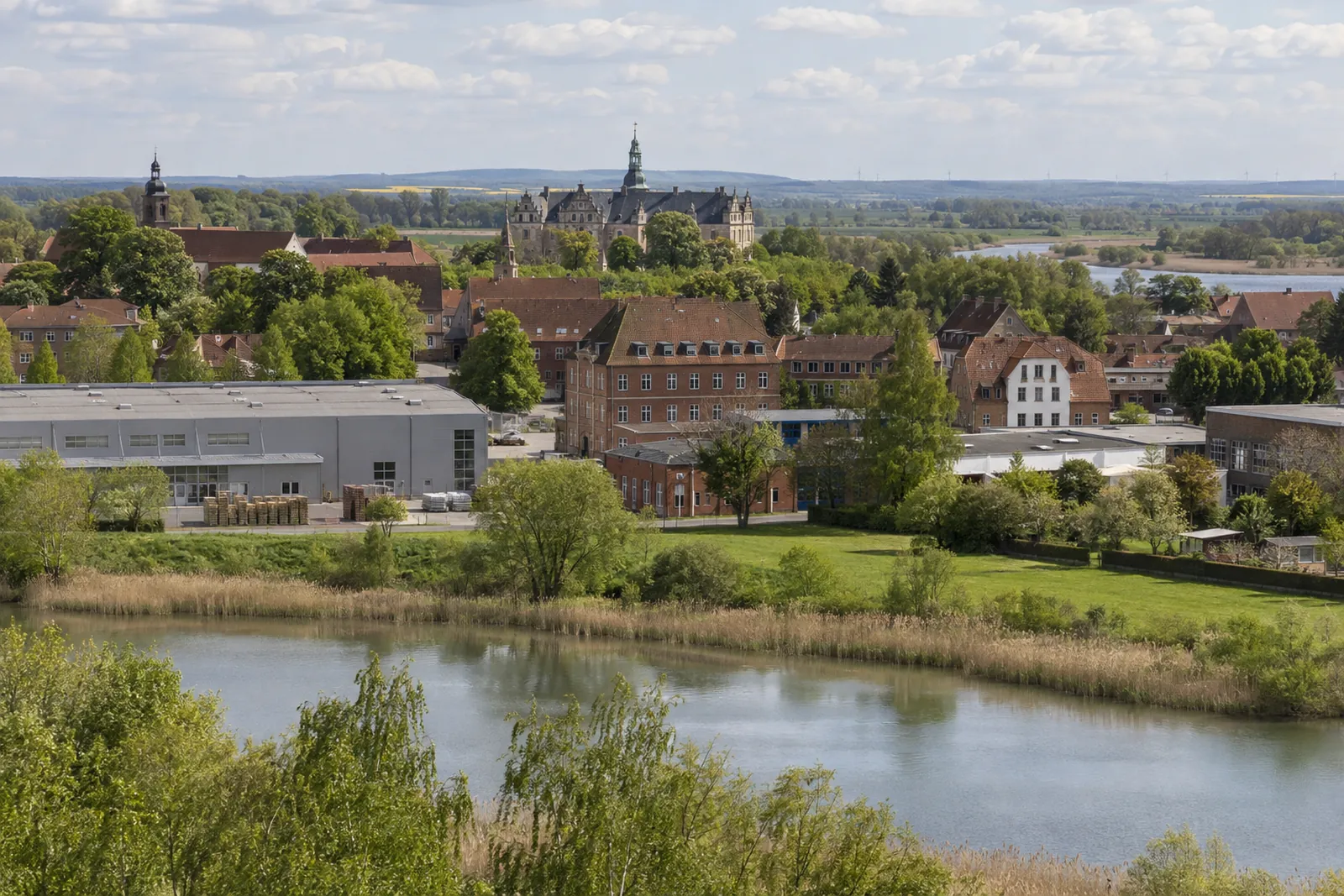 Gewerbebauten aus Backstein und eine Halle in Flusslandschaft bei Neustadt am Rübenberge