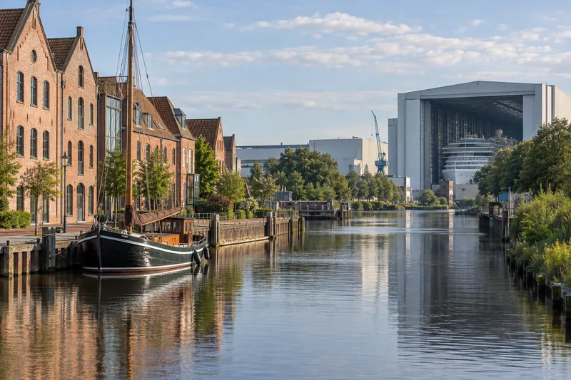Kanal in Papenburg mit Klinkergebäuden und großer Werfthalle am Horizont