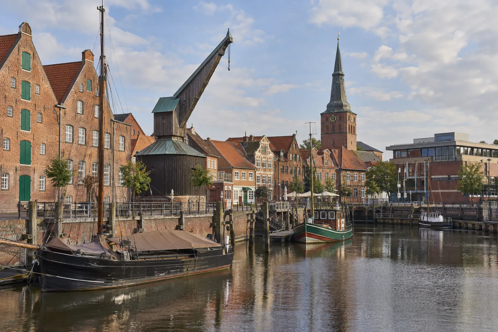 Backsteinspeicher und Giebelhäuser am Stader Hansehafen mit Kirchturm und modernem Bürobau im Hintergrund