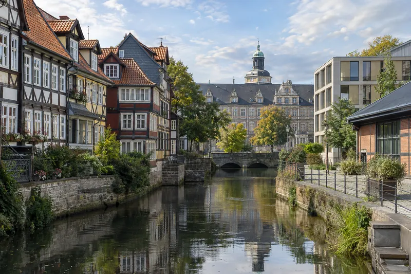 Fachwerkhäuser und moderne Gewerbebauten am Wasser in der Altstadt von Wolfenbüttel, im Hintergrund das Schloss